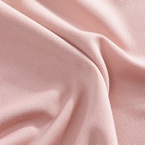 Close-up of pink quick-dry polo shirt fabric showing breathable honeycomb texture