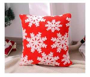 Gros plan d'une broderie de flocon rouge et blanc sur une housse de coussin de Noël