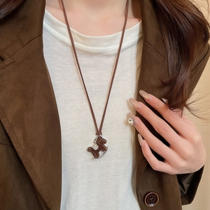 Detail of a brown flocked rocking horse necklace with zircon stones worn by a model
