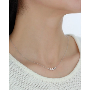 Detail of S925 silver clover necklace with small gemstones worn on a woman's neck