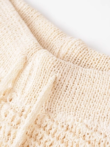 Detailed macro view of beige knitted fabric texture with elastic waistband structure