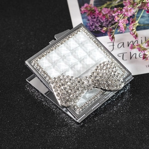 Sparkling square folding makeup mirror with rhinestone bow on black glitter surface