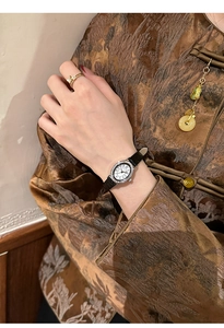 Close-up of elegant oval diamond-set watch with black leather strap on a model wrist