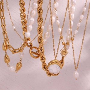 Detail of layered gold necklaces with white baroque pearls and a sun pendant design