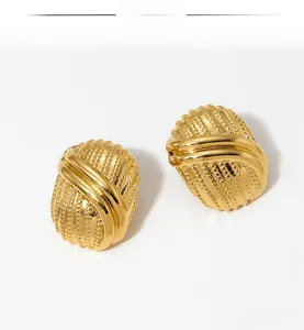 Detail of gold oval stud earring featuring textured spiral patterns and a smooth center band