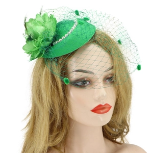 Detail of green fascinator hat with elegant pearls, floral accents and mesh veil on model