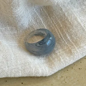 Detailed view of a gray marble pattern resin open ring on a textured fabric surface