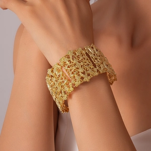 Détail d'un large bracelet manchette doré vintage avec gravures florales ajourées complexes