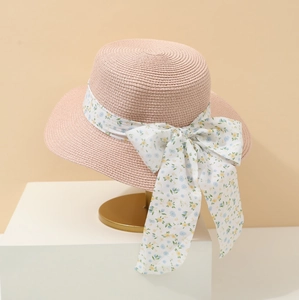 Detailaufnahme rosa Strohhut mit floraler Schleife auf elegantem Metallständer präsentiert