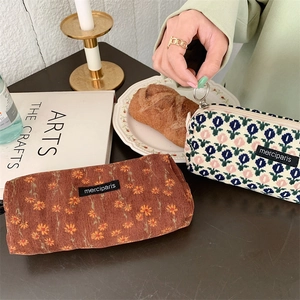 Detail of corduroy and knit cosmetic bags with floral embroidery and metal ring zippers