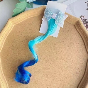 Close-up of sparkling blue sequin bow hair clip with curly gradient blue extensions