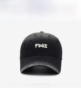 Close-up of charcoal gray washed denim baseball cap with white FBQE letter embroidery