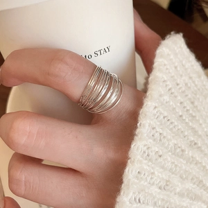 Close-up of layered silver ring band worn with a white cozy knitted sweater backdrop