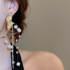 Macro detail of leaf-shaped earring with dangling pearls and zircon-studded chains