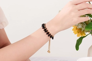 Detail of adjustable black beaded bracelet with gold spheres and sliding toggle clasp