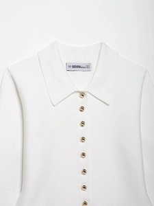 Detail of white knit polo cardigan with gold spherical buttons and ribbed turn-down collar