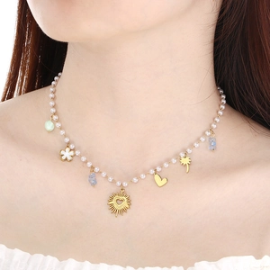 Detailed view of pearl necklace with gold heart and flower pendants on a model
