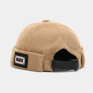 Détail du bonnet docker en velours côtelé kaki avec sangle en cuir noir et patch de marque