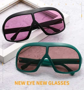 Detail of oversized retro sunglasses in black and green frames with tinted lenses