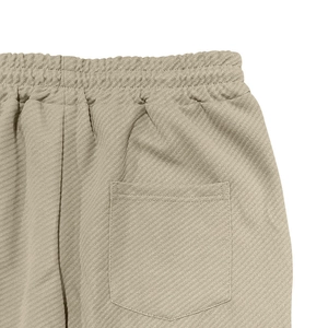 Detail view of elastic waist and back pocket on beige twill waffle texture pants