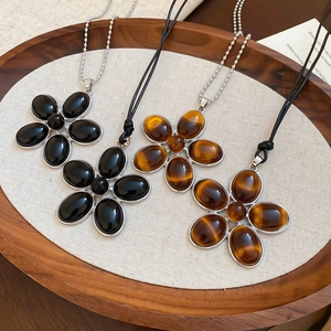 Macro detail of geometric resin flower pendants in black and tiger eye colors