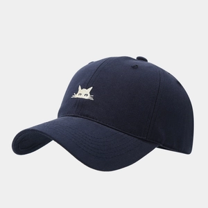 Detail of navy blue baseball cap featuring intricate white cat embroidery on premium fabric
