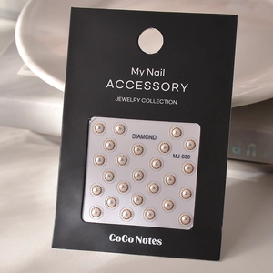 Macro detail of 5D gold embossed pearl nail art stickers on a black display card