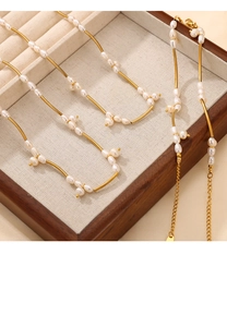Macro view of freshwater pearls and golden metal tubes on a titanium steel necklace