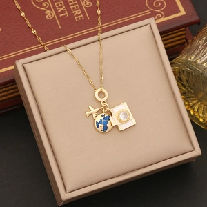 Detailed close-up of gold airplane, globe, and passport charms on a travel necklace