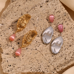 Detail of butterfly wing gold and silver earrings with pink teardrop stone pendants