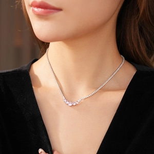 Close-up of elegant tennis necklace featuring pink round gemstones on a silver chain