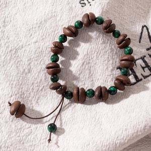 Detail of coffee bean wooden beads and green tiger eye stones on rustic linen fabric