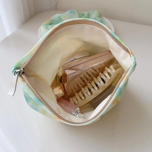 Detailed close-up of a tie-dye makeup bag with zipper showing interior storage space