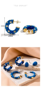 Detail view of blue enamel C-shaped hoop earrings with white crystals and gold finish