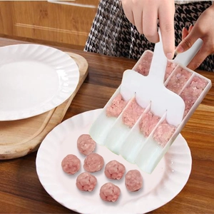 Action shot of white kitchen meatball maker set shaping meat paste on a wooden table