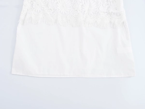Detailed view of white blouse featuring romantic lace patterns and tassel fringe trim