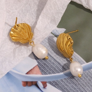 Gros plan de boucles d'oreilles coquillages plaquées or 18 carats avec perles baroques