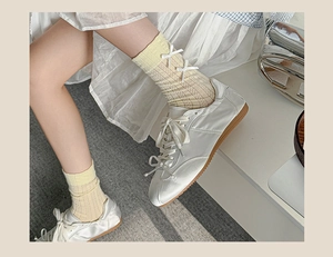 Close-up of knit pale yellow crew socks featuring a cute white ribbon bow detail