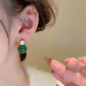 Close-up of vintage emerald green pearl earring with cubic zirconia on model's ear