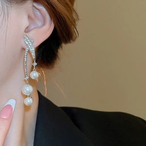 Gros plan de longues boucles d'oreilles à pompons avec cristaux brillants et perles sur modèle
