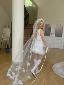 Detail of white bridal veil with bow accents and mini feather wedding dress set