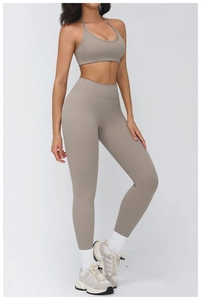 Side view of woman in taupe yoga set with halter sports bra and high waisted leggings