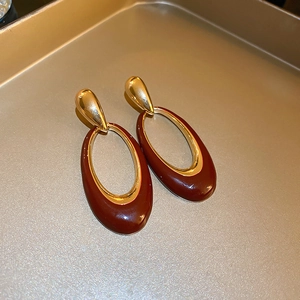 Close-up of vintage gold earrings with dark red enamel in a bronze jewelry tray