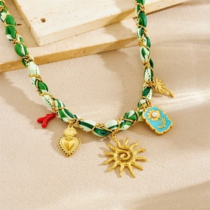 Gold chain necklace with green silk ribbon and assorted sun, flower, and heart pendants