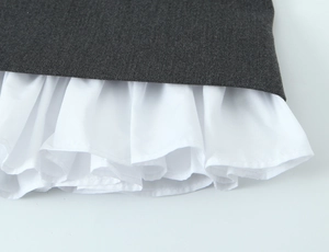 Detailed view of dark grey fabric layered with white pleated lining on a mini dress