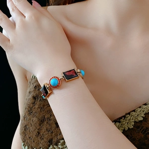 Detail of vintage gold bracelet with square ruby and round turquoise stones on wrist