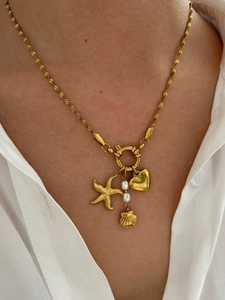 French INS style gold necklace with starfish, heart, shell and pearls on a model