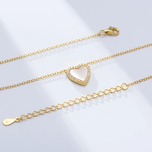 Detailed macro of gold-plated S925 silver heart necklace with white shell and zircons