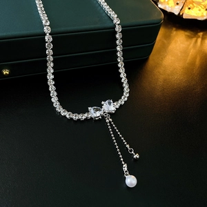 Silver bow necklace with zircon pavé, asymmetric chain tassels and white pearl charms