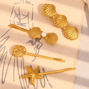 Golden starfish and scallop hair clip set with pearl accent on textured background